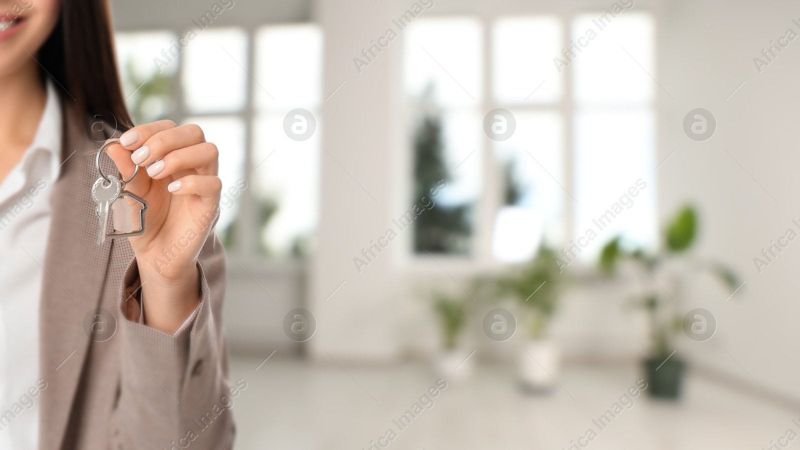 Real estate agent with house key indoors, closeup. Banner with space for text Image of Real estate agent with house key indoors, closeup. Banner with space for text