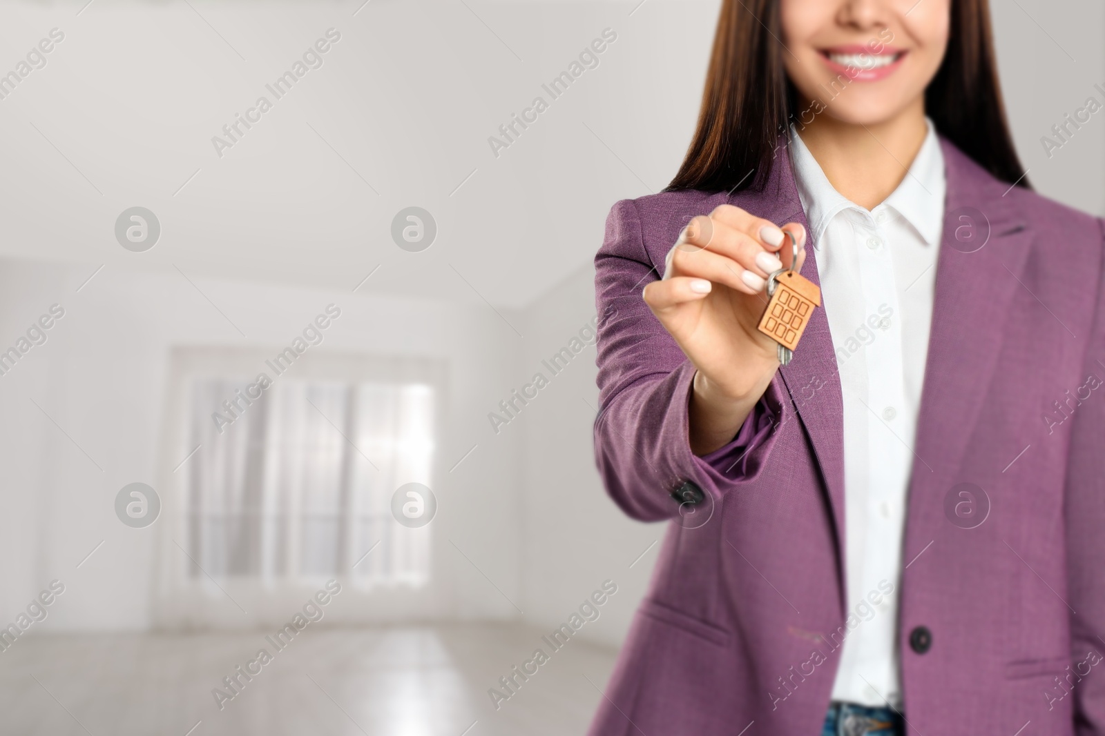 Real estate agent with house key in room, closeup. Space for text Image of Real estate agent with house key in room, closeup. Space for text