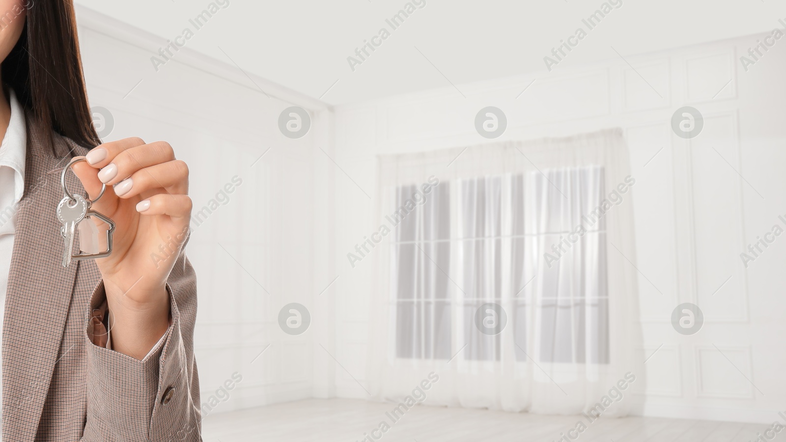 Real estate agent with house key in room, closeup. Banner with space for text Image of Real estate agent with house key in room, closeup. Banner with space for text