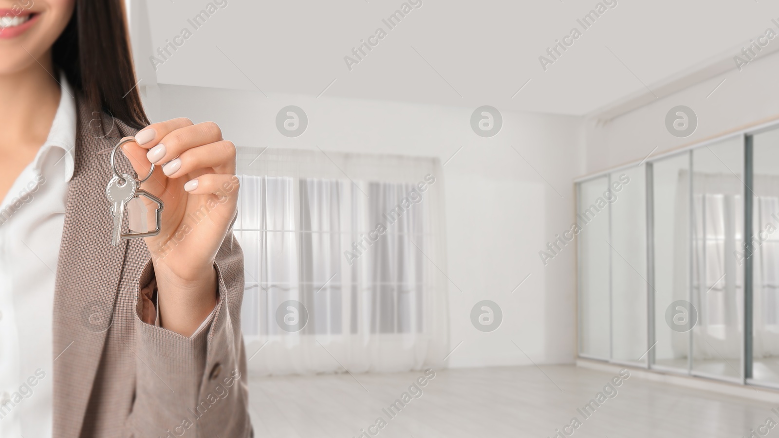 Real estate agent with house key in room, closeup. Banner with space for text Image of Real estate agent with house key in room, closeup. Banner with space for text