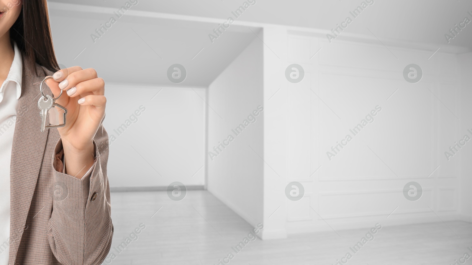Real estate agent with house key in room, closeup. Banner with space for text Image of Real estate agent with house key in room, closeup. Banner with space for text