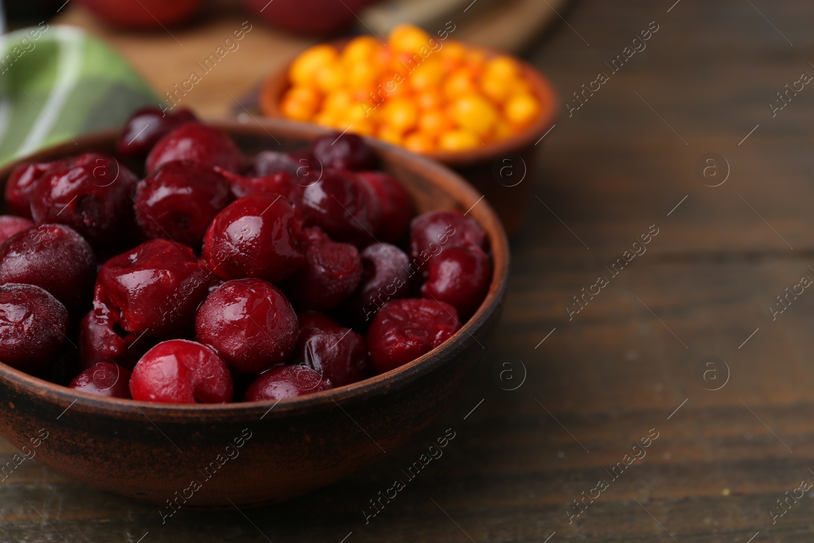 Tasty cherries and sea buckthorn berries on wooden table, closeup. Space for text Photo of Tasty cherries and sea buckthorn berries on wooden table, closeup. Space for text