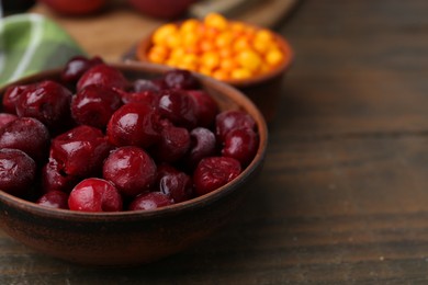 Photo of Tasty cherries and sea buckthorn berries on wooden table, closeup. Space for text