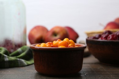 Photo of Tasty sea buckthorn berries, cherries and apples on wooden table, closeup