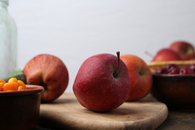 Photo of Apples, tasty cherries and sea buckthorn berries on wooden table, closeup