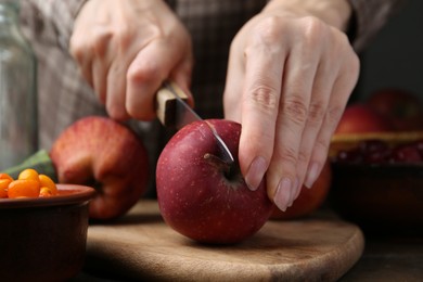 Photo of Woman cutting apples at wooden table, closeup