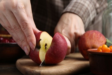 Photo of Woman cutting apples at wooden table, closeup