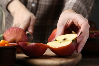 Photo of Woman cutting apples at wooden table, closeup