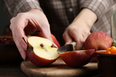 Photo of Woman cutting apples at wooden table, closeup