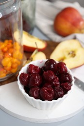 Photo of Tasty cherries, apples and sea buckthorn berries on light grey table, closeup