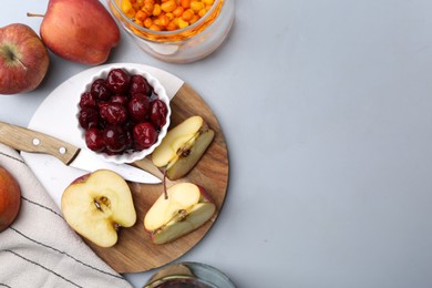 Photo of Tasty cherries, apples and sea buckthorn berries on light grey table, flat lay. Space for text