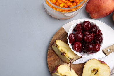 Photo of Tasty cherries, apples and sea buckthorn berries on light grey table, flat lay. Space for text