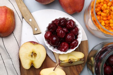 Photo of Tasty cherries, apples and sea buckthorn berries on light grey table, flat lay