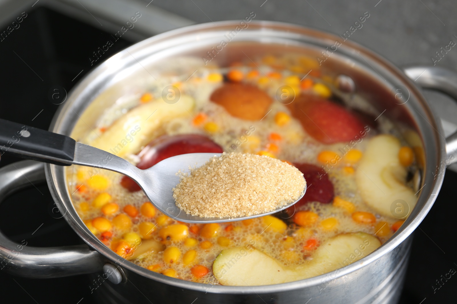 Adding sugar into tasty compot in pot on stove, closeup Photo of Adding sugar into tasty compot in pot on stove, closeup
