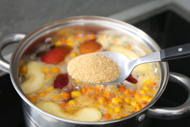 Photo of Adding sugar into tasty compot in pot on stove, closeup