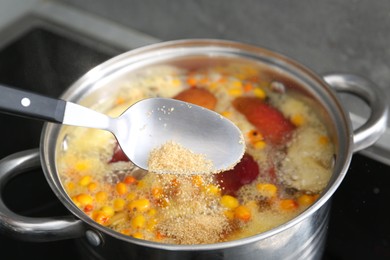 Photo of Adding sugar into tasty compot in pot on stove, closeup