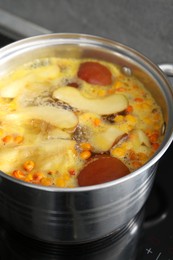 Photo of Making compot of apples and sea buckthorn berries. Simmering fruits in pot on stove, closeup