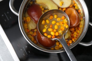 Photo of Taking tasty compot with ladle from pot on stove, top view