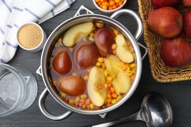 Photo of Tasty compot of apples and sea buckthorn berries in pot on grey wooden table, flat lay
