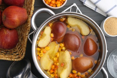 Photo of Tasty compot of apples and sea buckthorn berries in pot on grey wooden table, flat lay