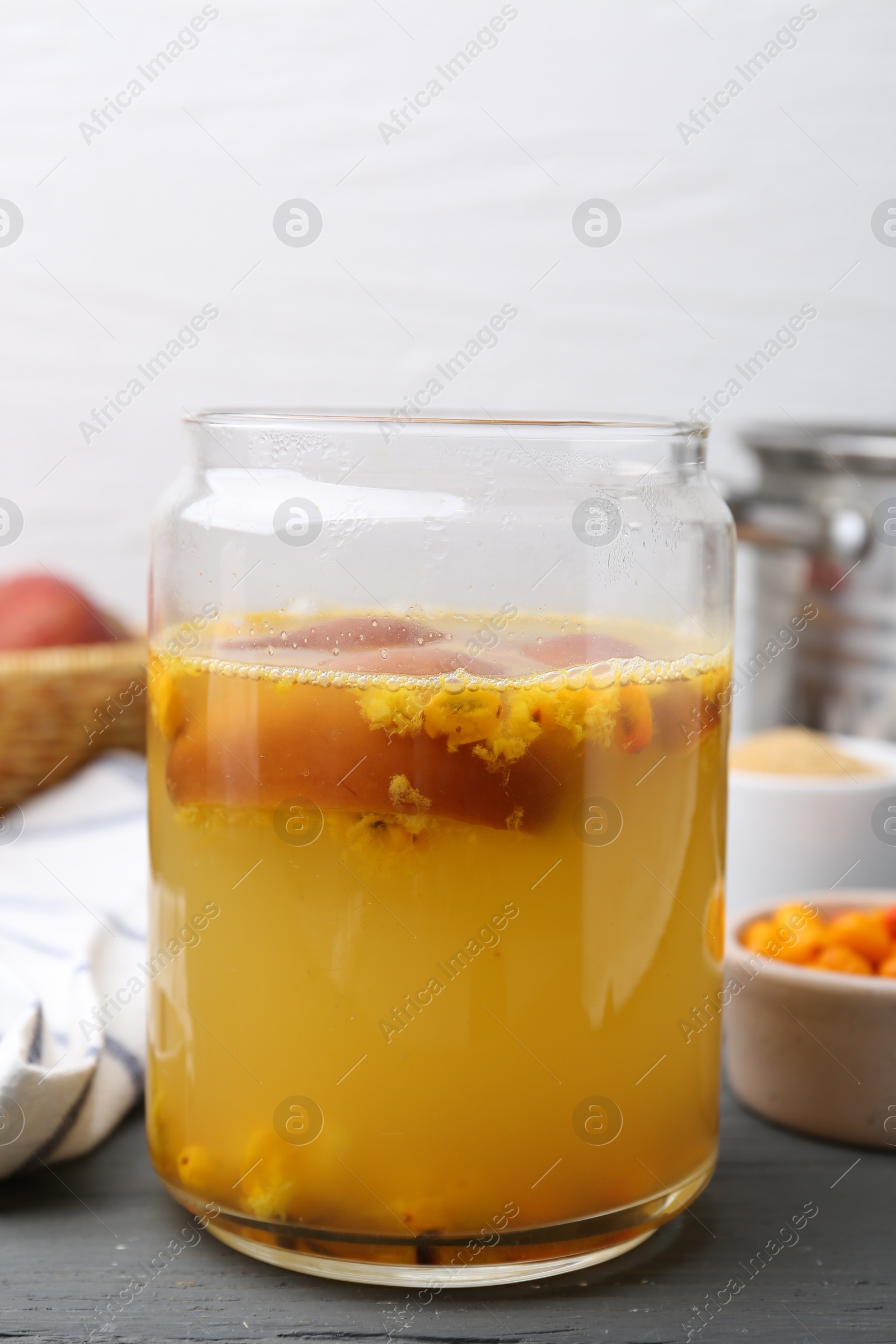 Photo of Tasty compot in glass jar and ingredients on grey wooden table, closeup