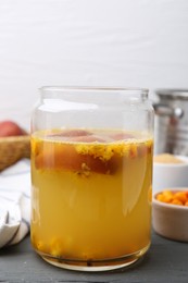Photo of Tasty compot in glass jar and ingredients on grey wooden table, closeup