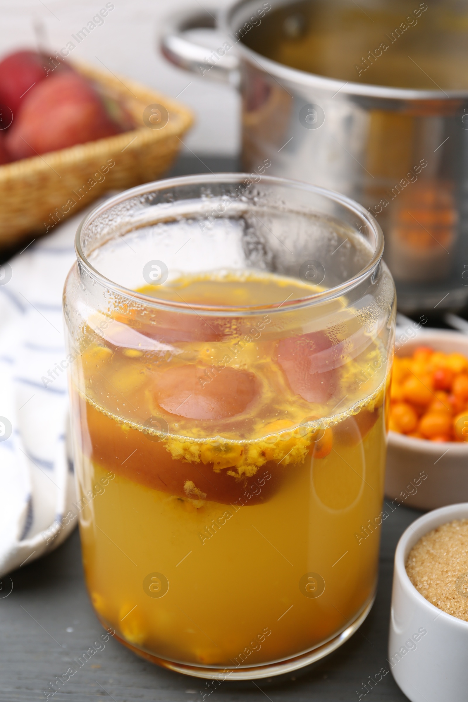 Photo of Tasty compot in glass jar and ingredients on grey wooden table, closeup