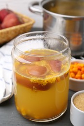 Photo of Tasty compot in glass jar and ingredients on grey wooden table, closeup