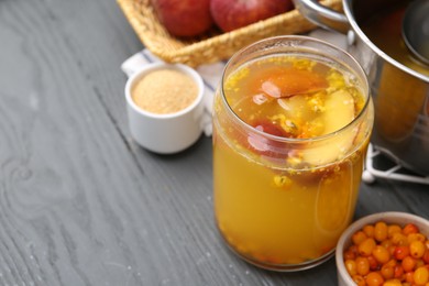 Photo of Tasty compot in glass jar and ingredients on grey wooden table, closeup. Space for text