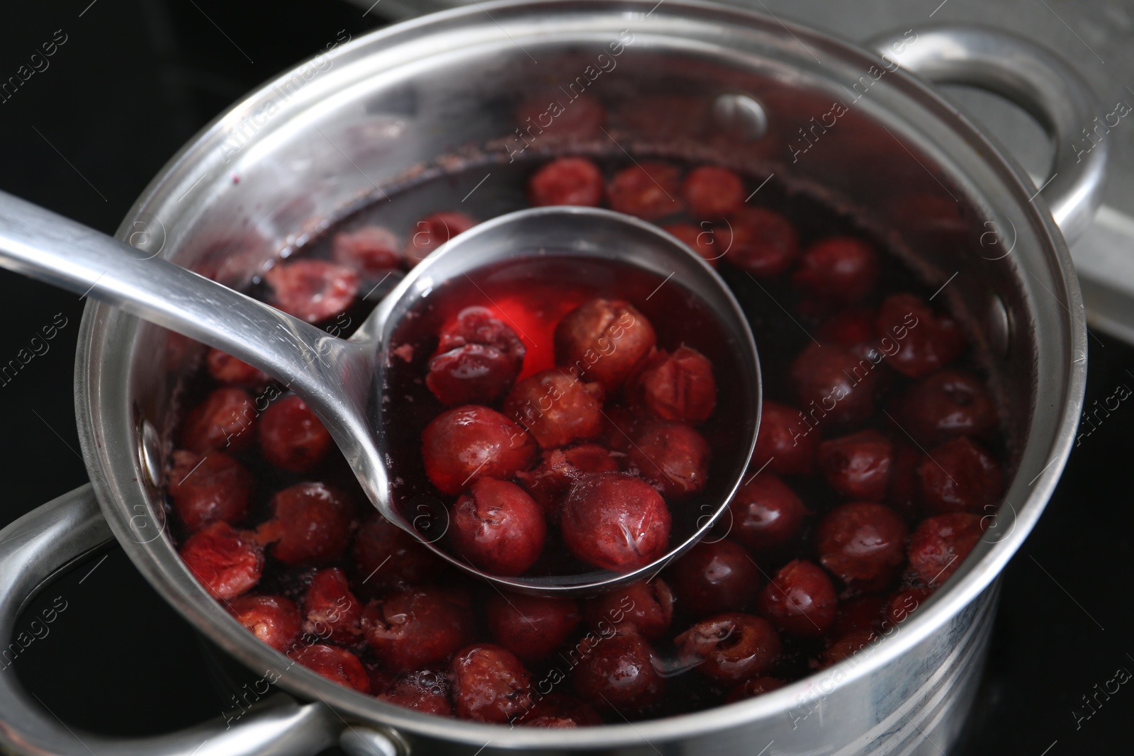 Photo of Making compot of cherries. Simmering fruits in pot on stove, closeup