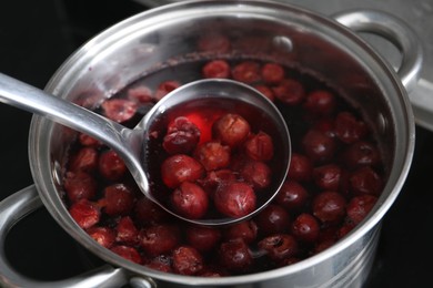 Photo of Making compot of cherries. Simmering fruits in pot on stove, closeup