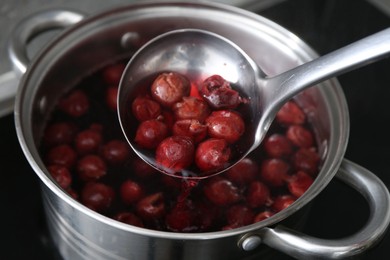 Photo of Making compot of cherries. Simmering fruits in pot on stove, closeup