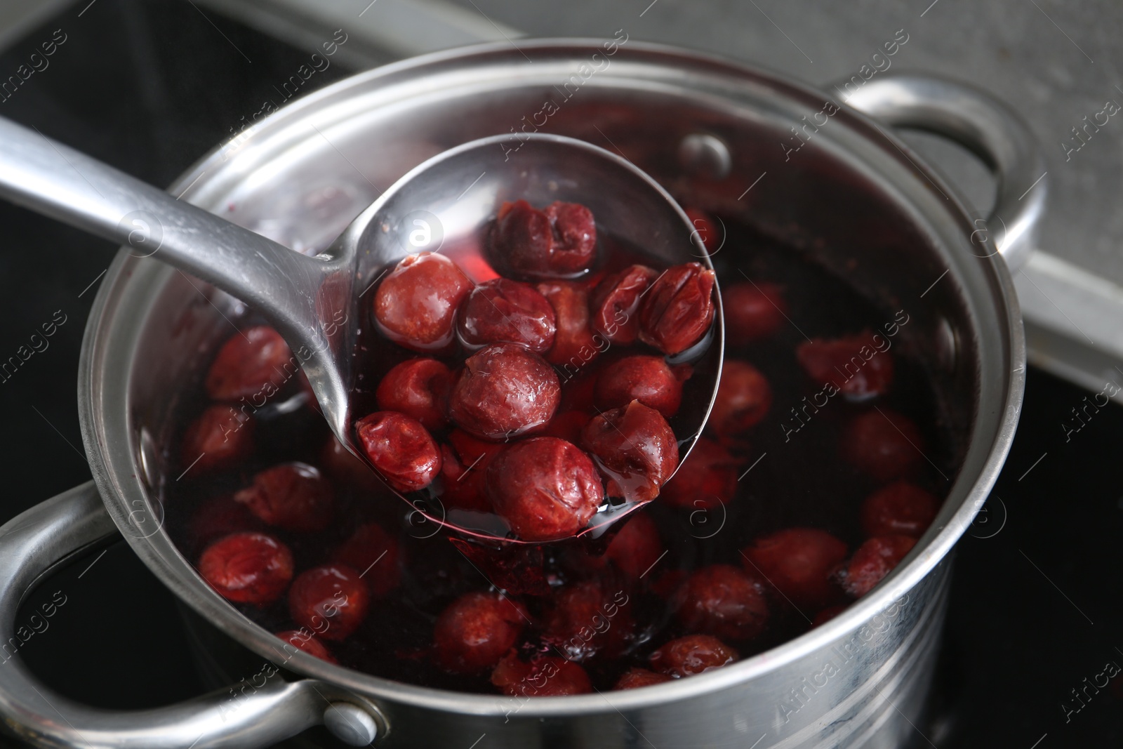 Making compot of cherries. Simmering fruits in pot on stove, closeup Photo of Making compot of cherries. Simmering fruits in pot on stove, closeup