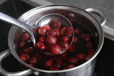 Photo of Making compot of cherries. Simmering fruits in pot on stove, closeup