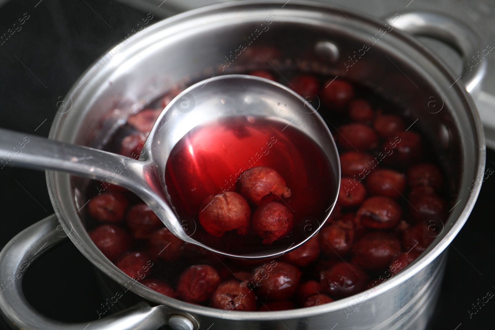 Making compot of cherries. Simmering fruits in pot on stove, closeup Photo of Making compot of cherries. Simmering fruits in pot on stove, closeup