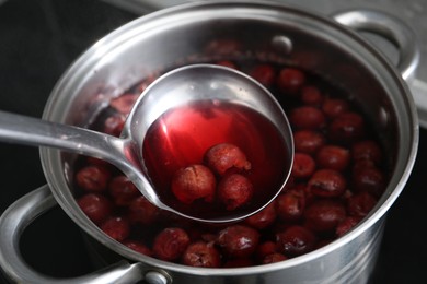 Photo of Making compot of cherries. Simmering fruits in pot on stove, closeup