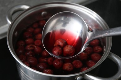 Photo of Making compot of cherries. Simmering fruits in pot on stove, closeup