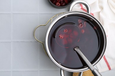 Photo of Tasty cherry compot in pot on white tiled table, flat lay. Space for text