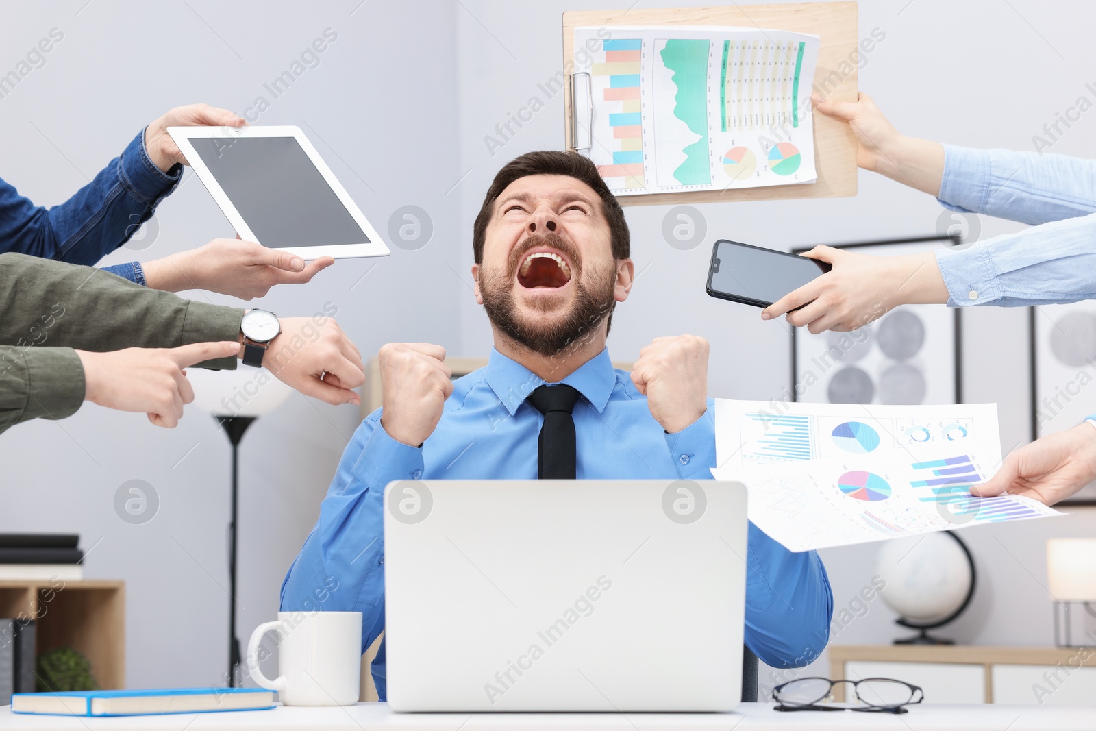Man overwhelmed by different requests from colleagues at desk in office Photo of Man overwhelmed by different requests from colleagues at desk in office