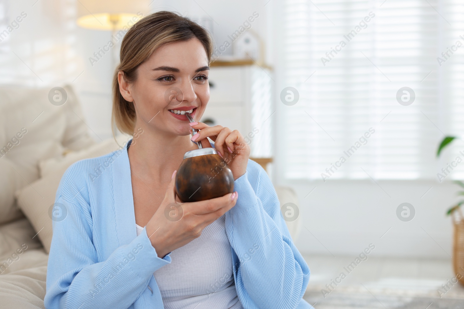 Woman drinking traditional yerba mate tea at home, space for text Photo of Woman drinking traditional yerba mate tea at home, space for text