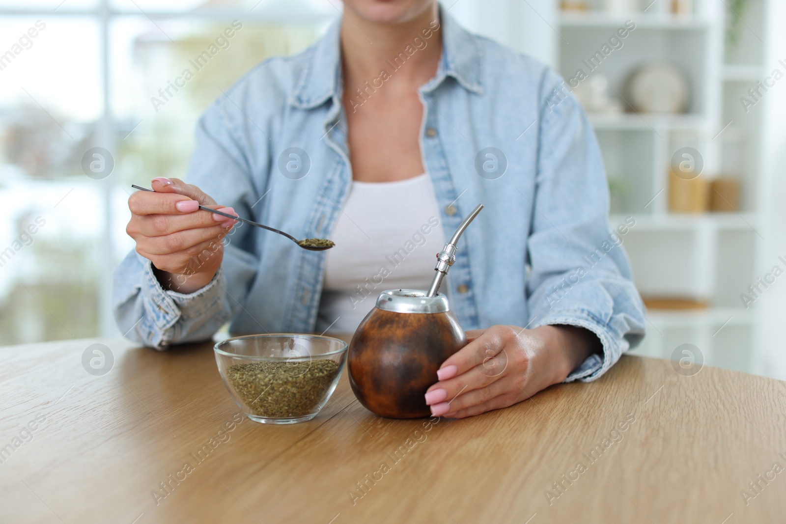 Woman making traditional yerba mate tea at wooden table indoors, closeup Photo of Woman making traditional yerba mate tea at wooden table indoors, closeup