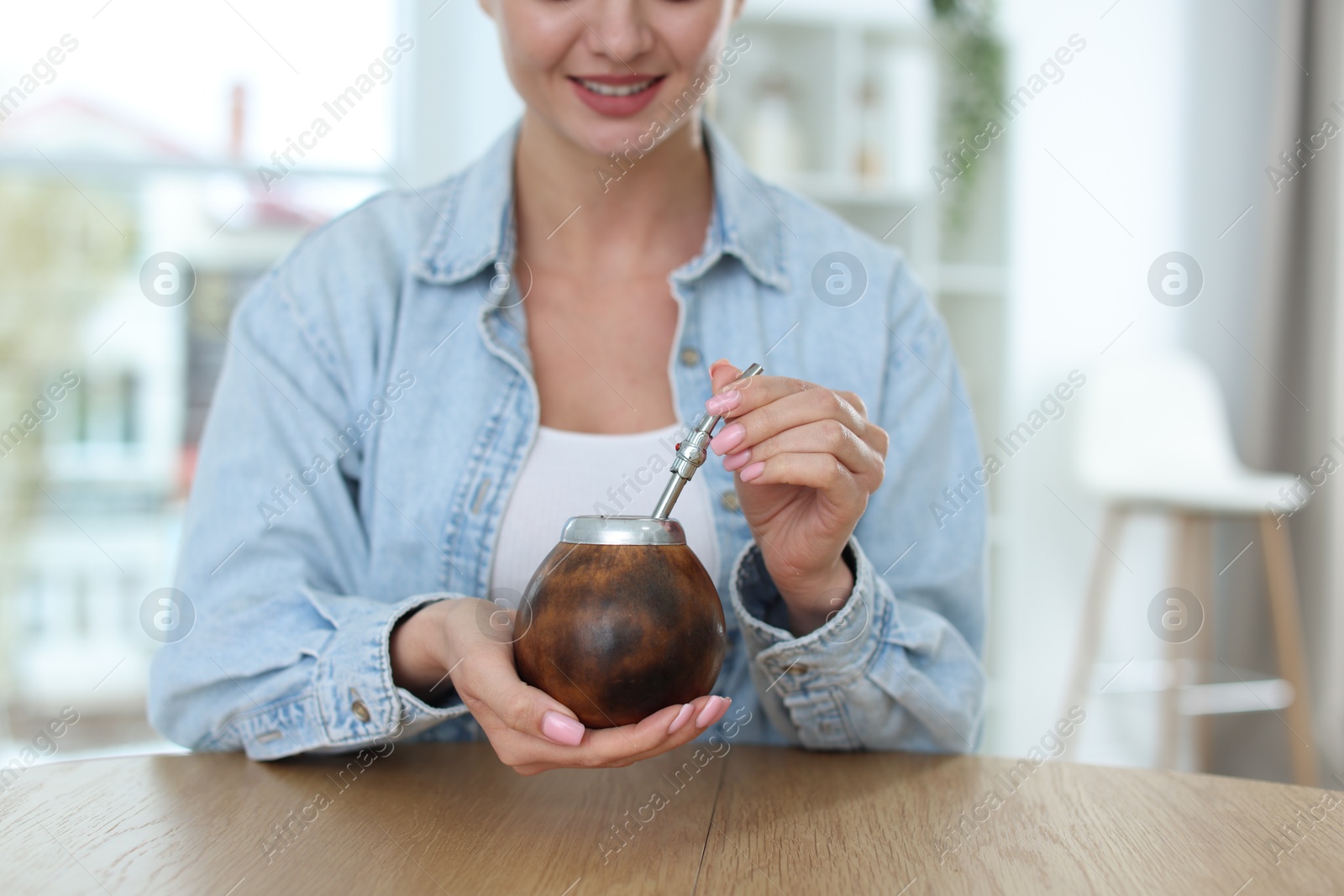 Woman with traditional yerba mate tea at table indoors, closeup. Space for text Photo of Woman with traditional yerba mate tea at table indoors, closeup. Space for text