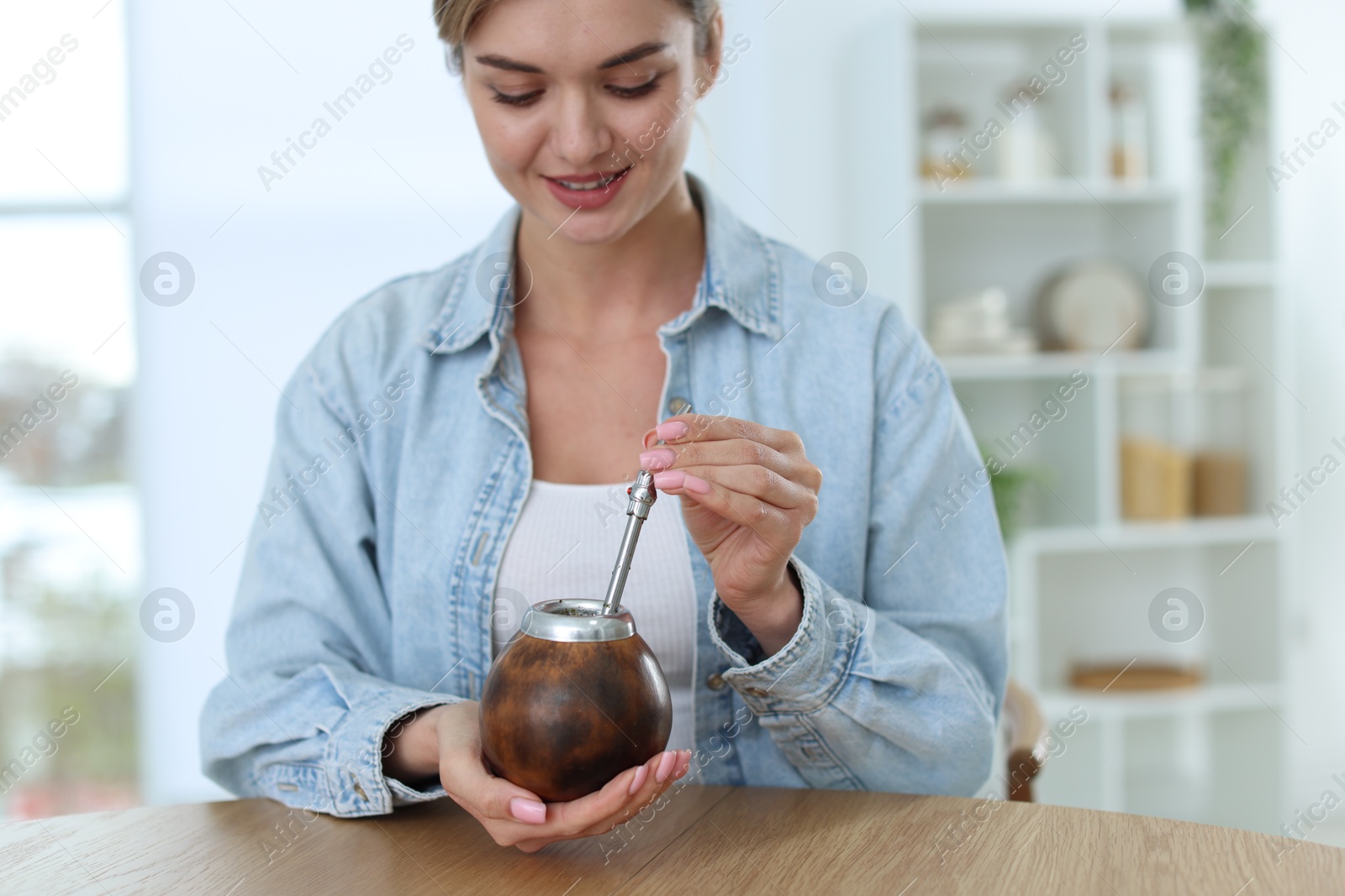 Woman with traditional yerba mate tea at table indoors Photo of Woman with traditional yerba mate tea at table indoors