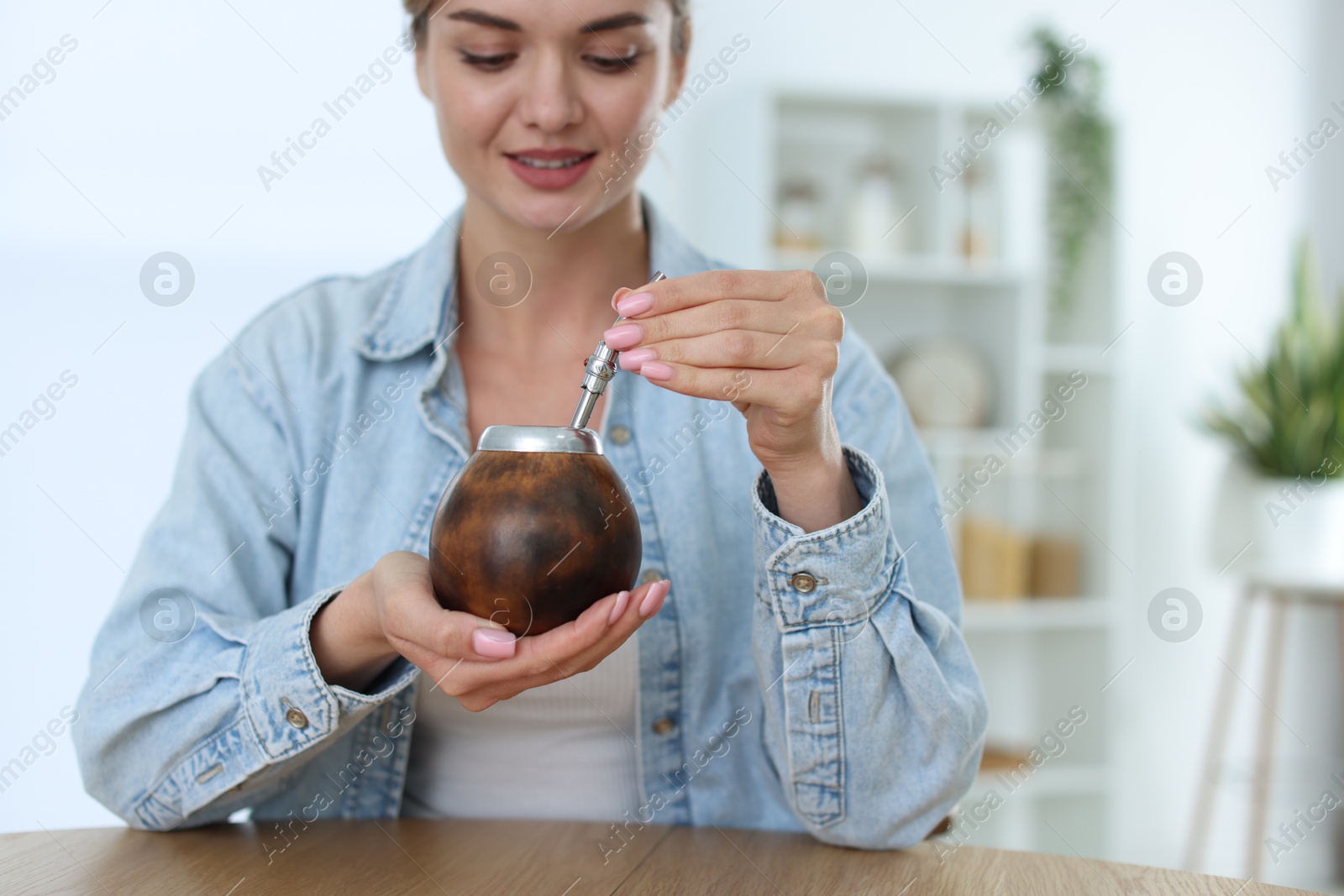 Woman with traditional yerba mate tea at table indoors, space for text Photo of Woman with traditional yerba mate tea at table indoors, space for text