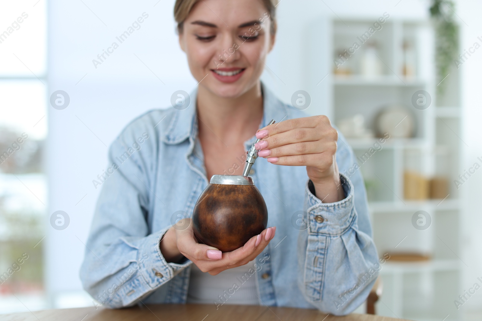 Woman with traditional yerba mate tea at table indoors, selective focus Photo of Woman with traditional yerba mate tea at table indoors, selective focus