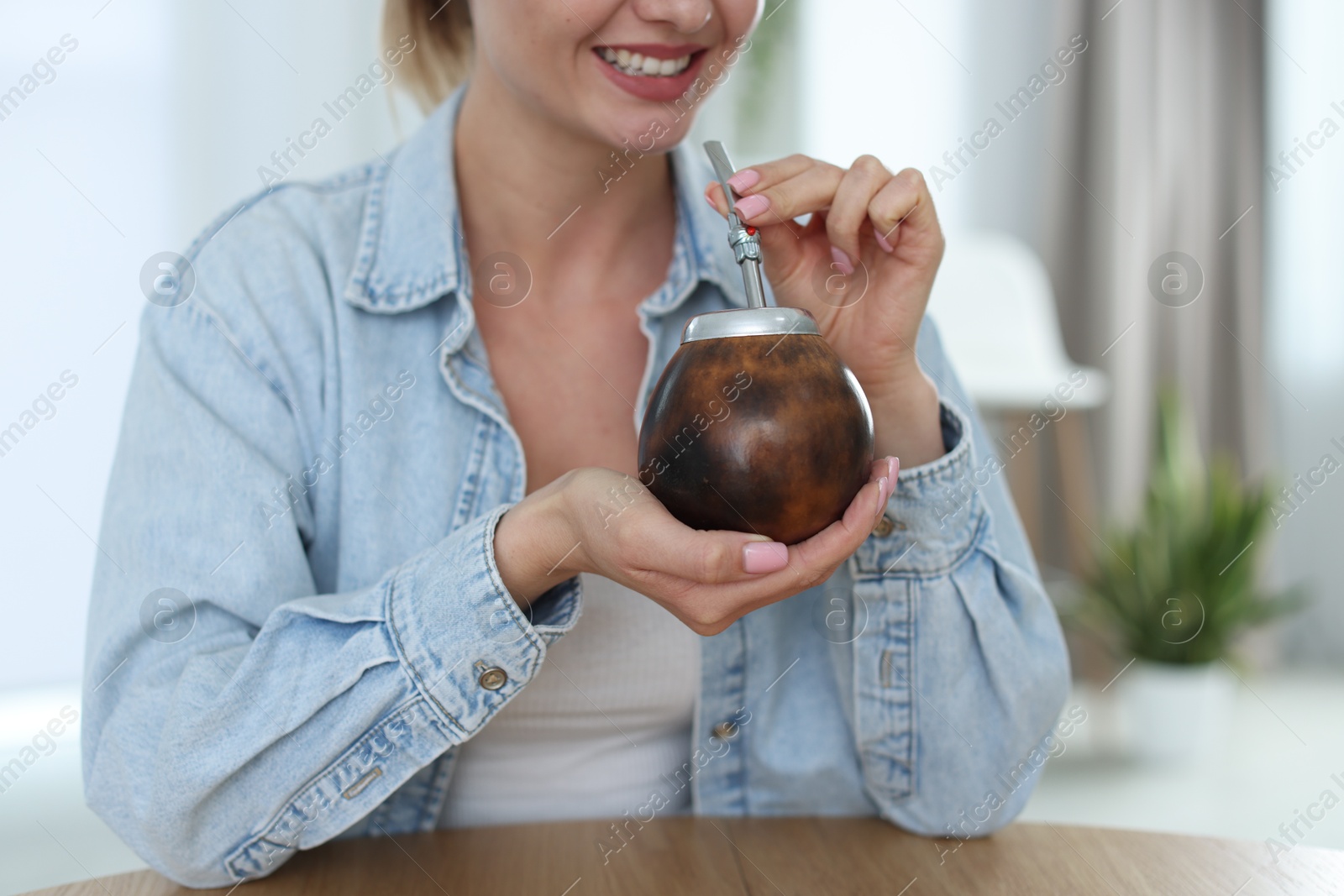 Woman with traditional yerba mate tea at table indoors, closeup Photo of Woman with traditional yerba mate tea at table indoors, closeup