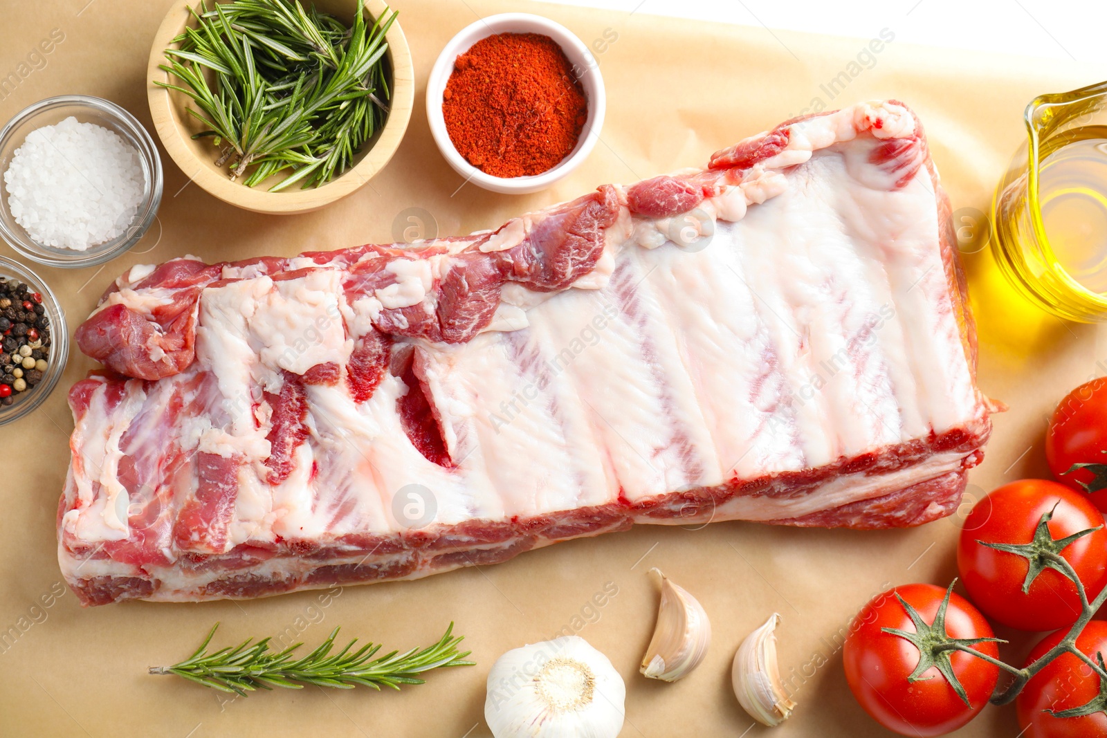 Raw pork ribs, spices and tomatoes on white table, flat lay Photo of Raw pork ribs, spices and tomatoes on white table, flat lay