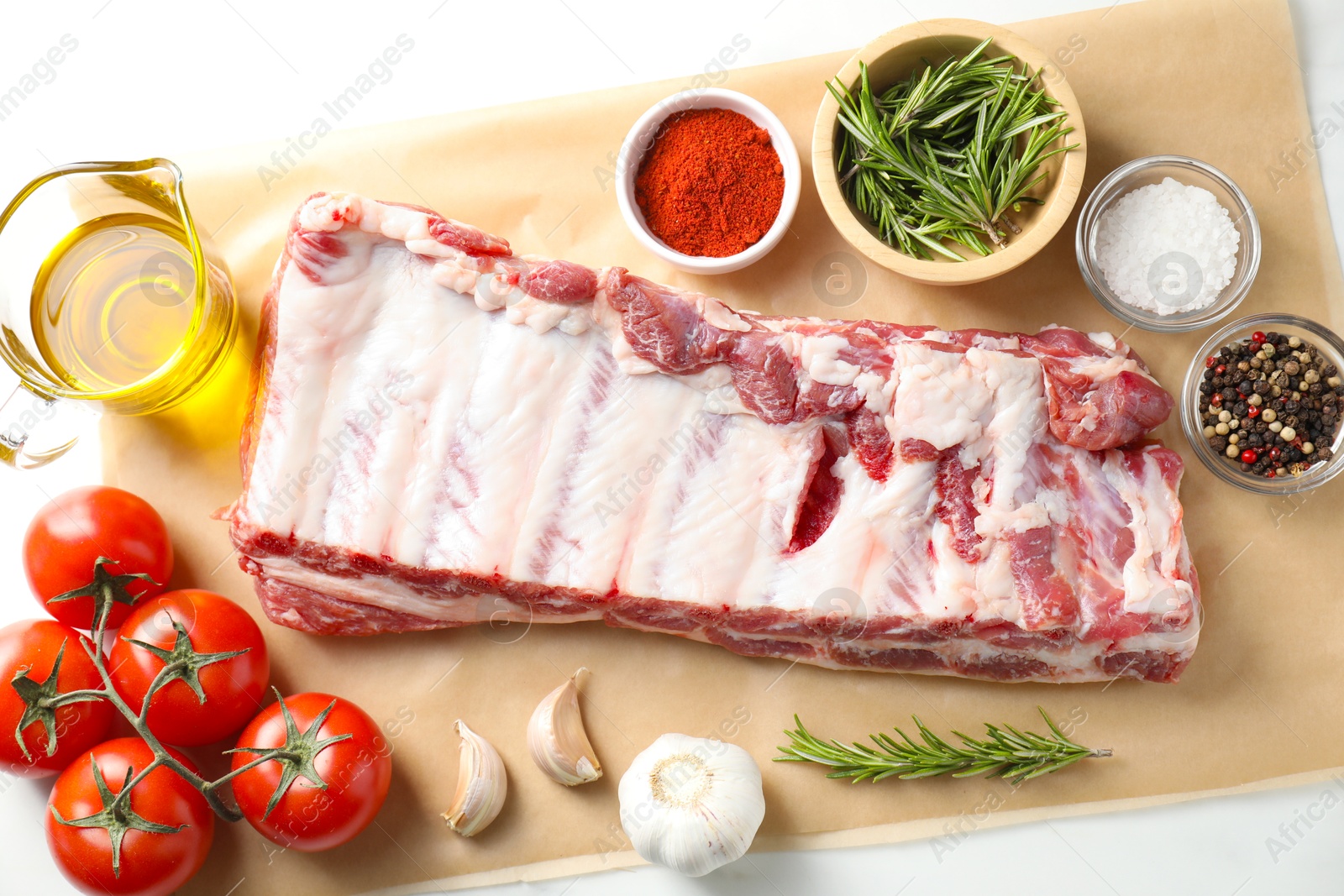 Raw pork ribs, spices and tomatoes on white table, flat lay Photo of Raw pork ribs, spices and tomatoes on white table, flat lay