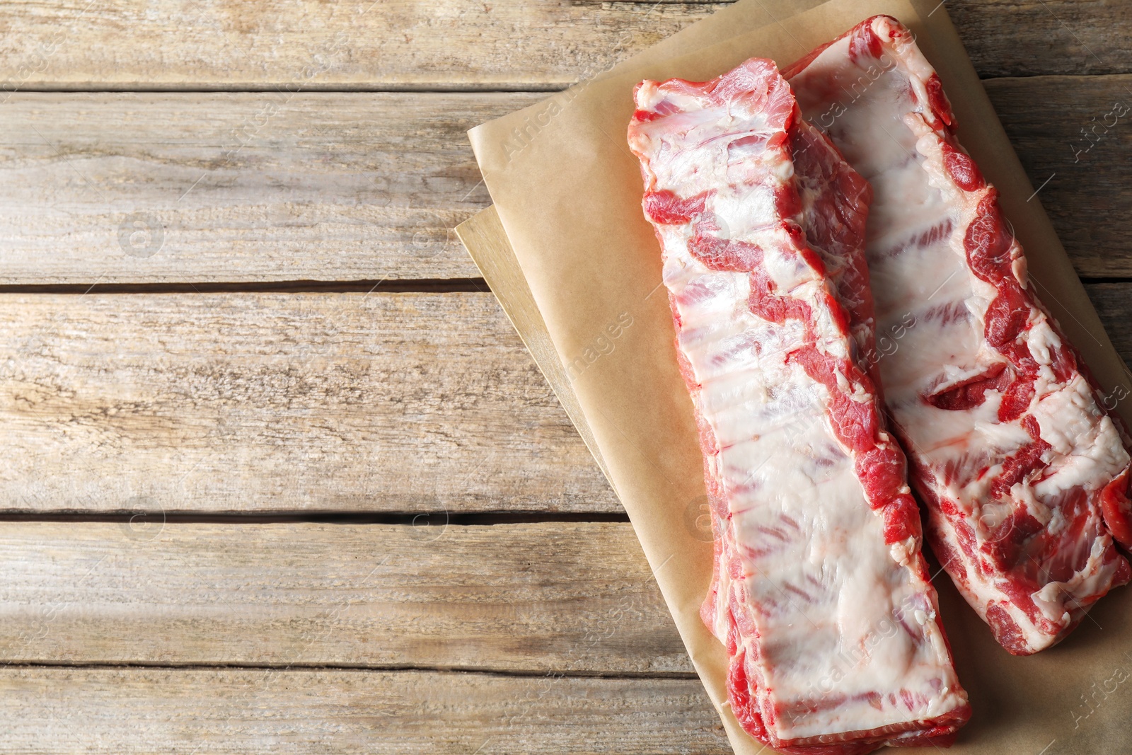 Raw pork ribs on wooden table, top view. Space for text Photo of Raw pork ribs on wooden table, top view. Space for text