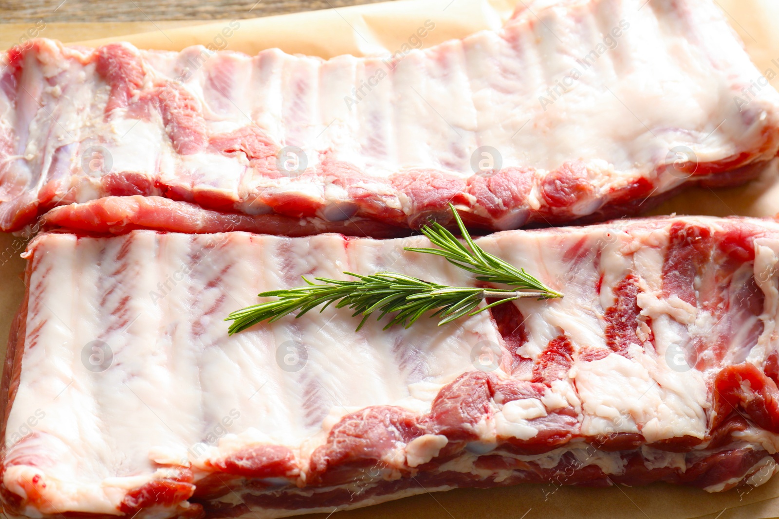 Raw pork ribs with rosemary on table, closeup Photo of Raw pork ribs with rosemary on table, closeup